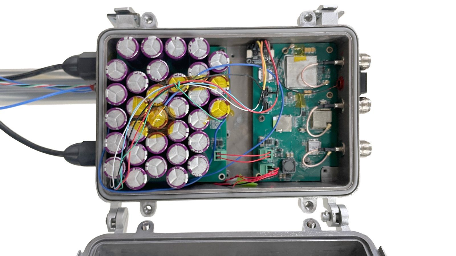 Interior of the LokoHUB enclosure showing the supercapacitor bank on the left and the ESP32-S3, LoRa concentrator and cellular boards on the right